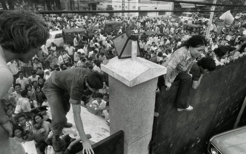 South Vietnamese civilians try to climb the wall of the embassy